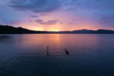 a person in a boat in a lake at sunset at Isla Chiquita Glamping Hotel in Puntarenas