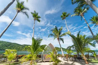 a boat on a beach with palm trees at Isla Chiquita Glamping Hotel in Puntarenas