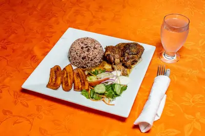 a plate of food with meat and vegetables and a drink at Hotel Pacuare in Siquirres