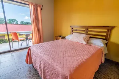 a bedroom with a bed and a view of a patio at Hotel Pacuare in Siquirres