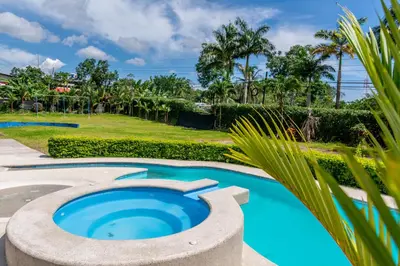 a large pool with a circular coping in a yard with palm trees at Hotel Pacuare in Siquirres