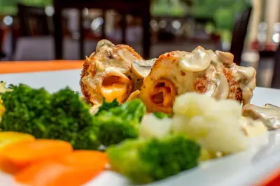 a plate of food with broccoli on a table at Hotel Pacuare in Siquirres