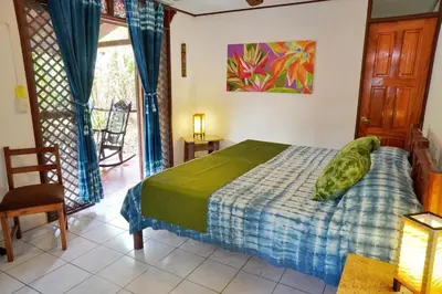a bedroom with a bed and a chair and a window at La Quinta Sarapiqui Lodge in Sarapiquí