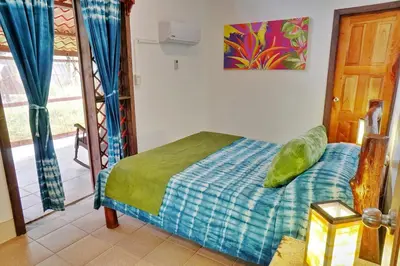 a bedroom with a bed with a blue blanket at La Quinta Sarapiqui Lodge in Sarapiquí
