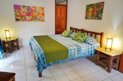 a bedroom with a bed in a room with two tables at La Quinta Sarapiqui Lodge in Sarapiquí