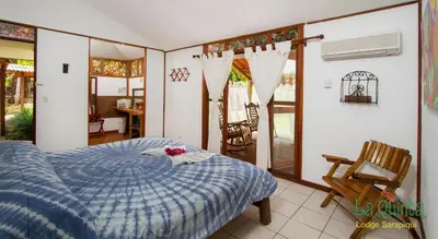 a bedroom with a bed with a blue comforter at La Quinta Sarapiqui Lodge in Sarapiquí