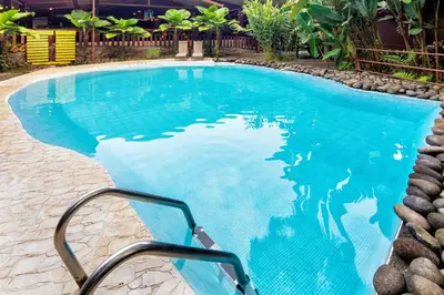 a large swimming pool with a stairway leading into it at La Quinta Sarapiqui Lodge in Sarapiquí