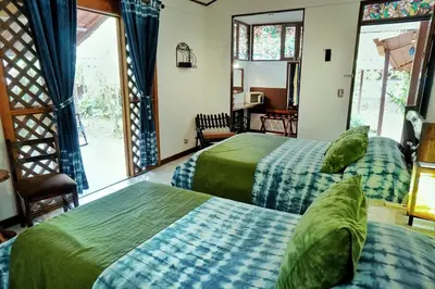 two beds in a room with two windows at La Quinta Sarapiqui Lodge in Sarapiquí