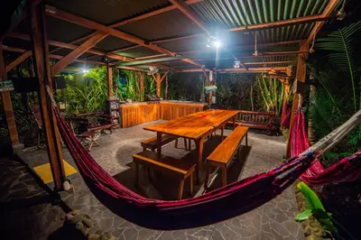 a hammock in a room with a table and benches at Villas Oasis in Manuel Antonio