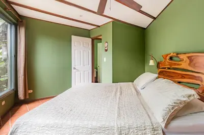 a bedroom with green walls and a large bed at Villas Oasis in Manuel Antonio