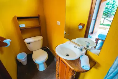 a yellow bathroom with a toilet and a sink at Pension Santa Elena in Monteverde Costa Rica