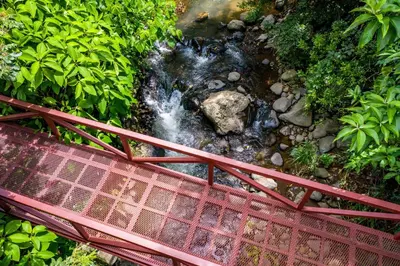 a red bridge over a creek with a stream at La Terraza Guest House B&B in Grecia