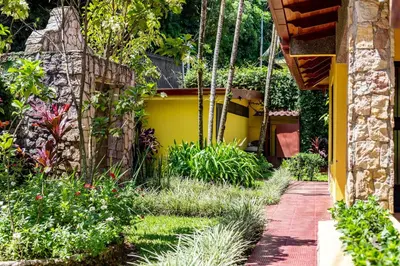 a garden with a yellow wall and a walkway at La Terraza Guest House B&B in Grecia