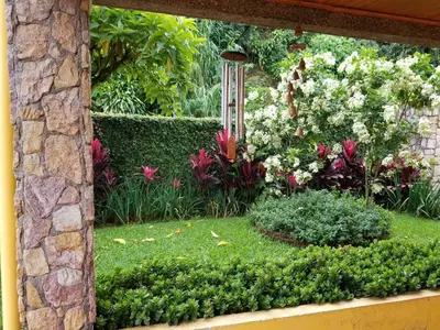 a garden with flowers and a stone wall at La Terraza Guest House B&B in Grecia