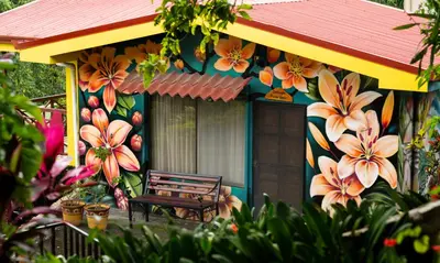a bench sitting outside of a house with flowers painted on it at La Terraza Guest House B&B in Grecia