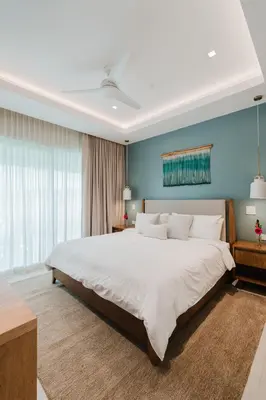a bedroom with a large white bed with a blue wall at Las Villas Marina Pez Vela in Quepos