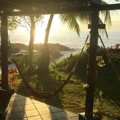 a hammock in a resort with a view of the ocean at Luminosa Montezuma Hostel in Montezuma