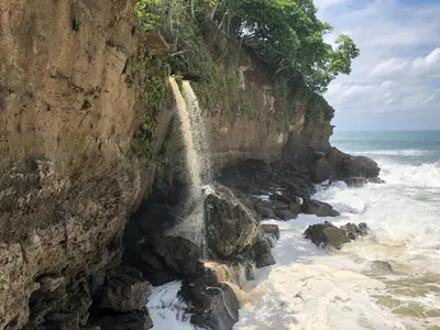a waterfall on a cliff next to the ocean at Luminosa Montezuma Hostel in Montezuma