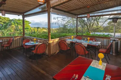 a restaurant with tables and chairs on a deck at Finca Rosa Blanca Coffee Farm and Inn in Heredia