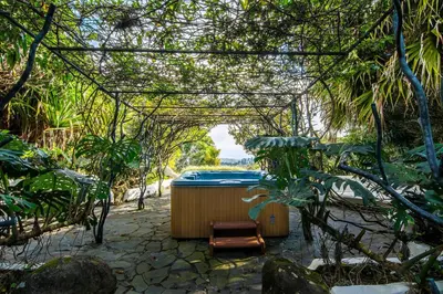 a jacuzzi tub in a garden with trees at Finca Rosa Blanca Coffee Farm and Inn in Heredia