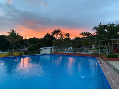 a large blue swimming pool with a sunset in the background at Hotel Palenque Tarrazu in San Marcos