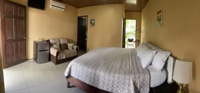 a bedroom with a bed and a chair at Aunty Arenal Lodge in Fortuna