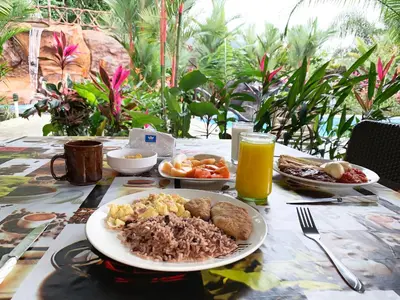 a table with a plate of breakfast food and orange juice at Aunty Arenal Lodge in Fortuna