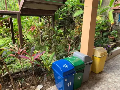 two trash cans sitting next to a building with plants at Aunty Arenal Lodge in Fortuna