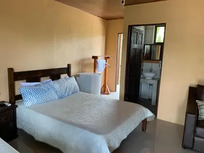 a bedroom with a bed and a bathroom with a sink at Aunty Arenal Lodge in Fortuna