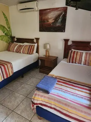 a bedroom with two beds and a night stand with a lamp at Hotel Villa Prats in Manuel Antonio