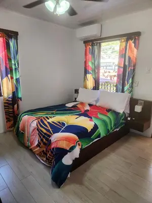 a bedroom with a bed with a colorful comforter at Hotel Villa Prats in Manuel Antonio