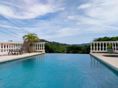 a swimming pool with a bench in the middle at Playa Flamingo penthouse with pacific sunset views - Flamingo Rose Vista in Playa Flamingo