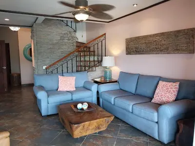 a living room with two blue couches and a table at Playa Flamingo penthouse with pacific sunset views - Flamingo Rose Vista in Playa Flamingo