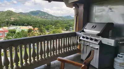 a balcony with a stove and a view of mountains at Playa Flamingo penthouse with pacific sunset views - Flamingo Rose Vista in Playa Flamingo