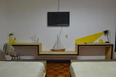 a room with two beds and a tv on the wall at Capital Hostel de Ciudad in San José