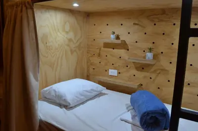a bed in a room with a wooden wall at Capital Hostel de Ciudad in San José