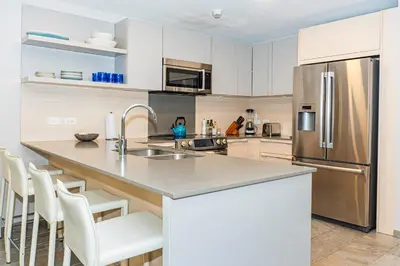 a kitchen with a stainless steel refrigerator and white cabinets at Elan at Ballena Beach in Uvita