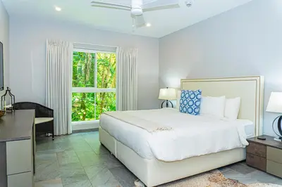 a bedroom with a bed and a desk and a window at Elan at Ballena Beach in Uvita