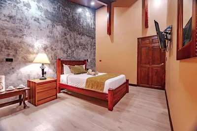a bedroom with a bed and a table and a lamp at Hotel Villa Florencia in Turrialba
