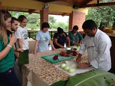 a man cutting a cake at a table with a group of people at Hotel Villa Florencia in Turrialba