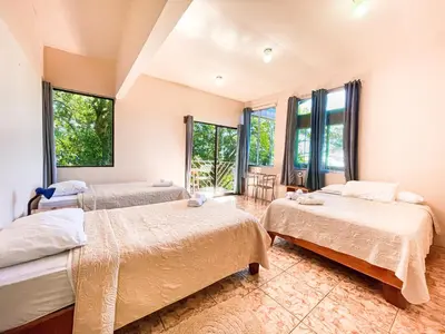 two beds in a room with windows at La Casa de la Montaña in Monteverde Costa Rica