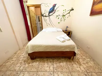 a bedroom with a bed with a bird on a branch at La Casa de la Montaña in Monteverde Costa Rica