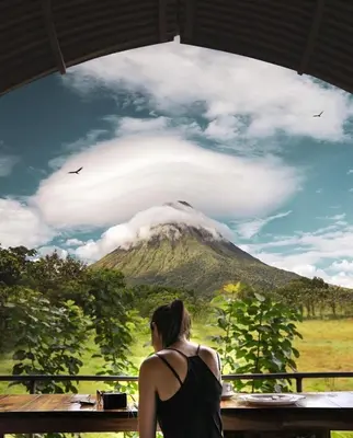 a woman sitting at a table looking at a mountain at Arenal Xilopalo in Fortuna