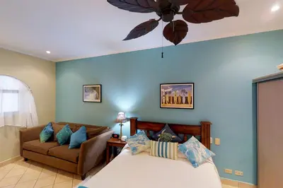 a bedroom with a bed and a couch and a ceiling fan at Sunrise 22 in Tamarindo