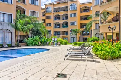 a courtyard with chairs and a swimming pool in front of a building at Sunrise 22 in Tamarindo