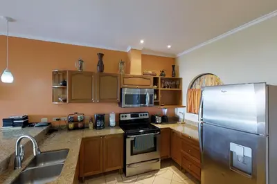 a kitchen with wooden cabinets and a stainless steel refrigerator at Sunrise 22 in Tamarindo