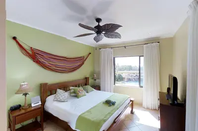 a bedroom with a bed with a ceiling fan and a window at Sunrise 22 in Tamarindo