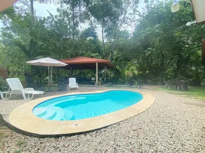 a swimming pool with a table and chairs and an umbrella at Ukinca in Uvita