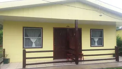 a yellow house with two windows and a door at Posada Rural Oasis in Caño Negro