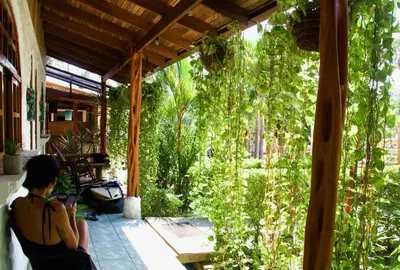a woman sitting on the porch of a house at Vida Hermosa in Playa Hermosa